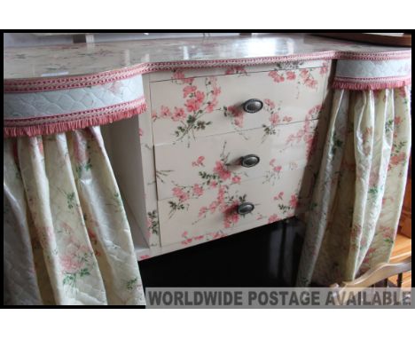 A chintzy retro vintage kidney shaped dressing table, with floral curtains to the front and mirror to the top. 