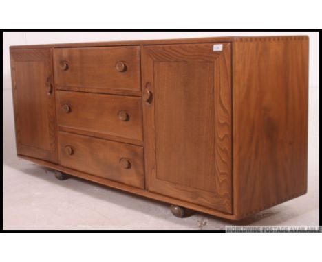 A stunning Ercol Windsor pattern low beech and elm sideboard. The low sideboard on ball castors with a bank of drawers flanke