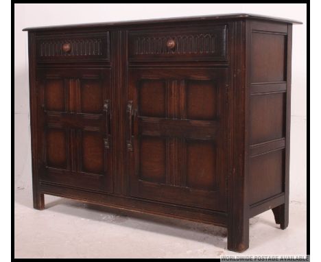A vintage mid century Ercol dark Elm dresser base, with two frieze drawers over two lower opposing twin panel doors, standing