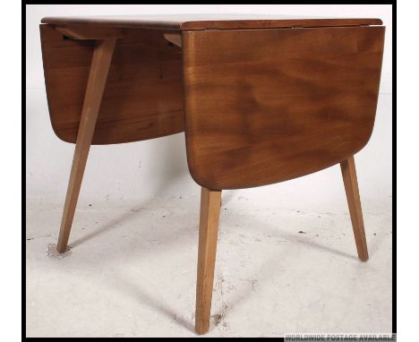 An Ercol Windsor pattern drop leaf dining table. beech and elm  construction raised on angled legs with drop leaves raised on