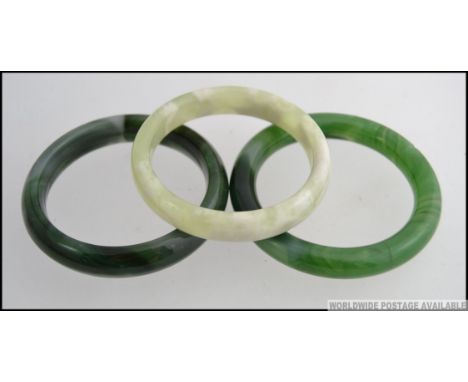 A group of 20th century Chinese  Jade bangles the first of circular form mottled dark green colouring along with two others o