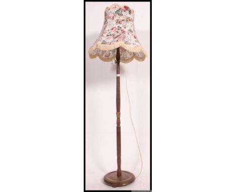 A mid 20th century turned oak standard lamp of usual form complete with a chintzy shade