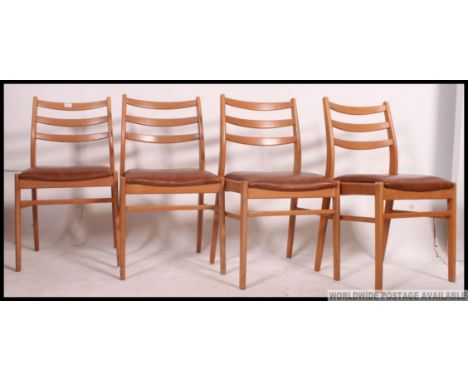 A set of 4 1960's light teak wood retro dining chairs. Raised on shaped legs with railed back rests and vinyl upholstered sea