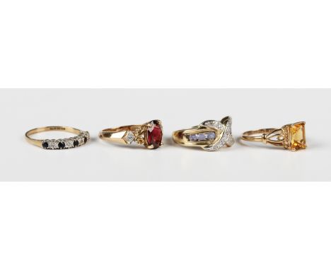 A 9ct gold, garnet and diamond three stone ring, claw set with the oval cut garnet between scroll pierced shoulders, each mou