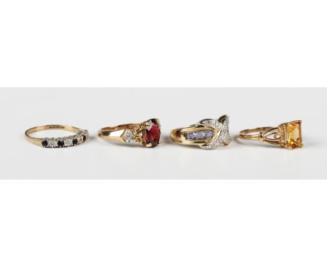 A 9ct gold, garnet and diamond three stone ring, claw set with the oval cut garnet between scroll pierced shoulders, each mou