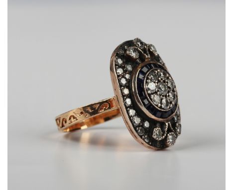 A rose gold, sapphire and diamond panel shaped ring, the centre cluster mounted with eight circular cut diamonds within a sur