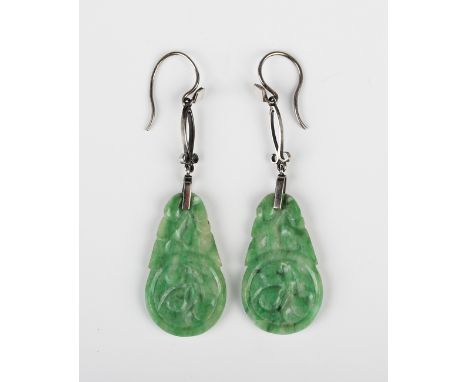 A pair of Chinese white gold mounted jade pendant earrings, 1920s/30s each drop carved with fruit motifs below a pierced scro