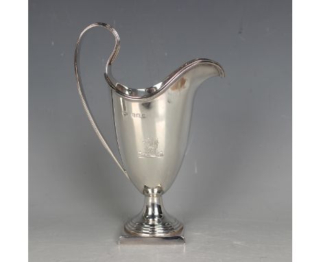 A George V silver helmet cream jug with reeded scroll handle, raised on a stepped circular foot and square base, Birmingham 1