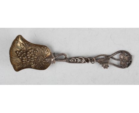 A mid-Victorian silver caddy spoon, the shovel shaped bowl embossed with fruiting vines, the cast and pierced handle formed a