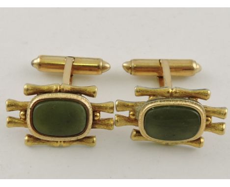 A pair of yellow metal and jade cufflinks, the oval cut stones mounted on a simulated bamboo ground.