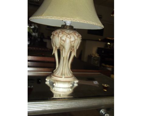 An early 20th Century ceramic oil lamp base, now converted to electricity, modelled in the form of elephants heads, H. 60cm.