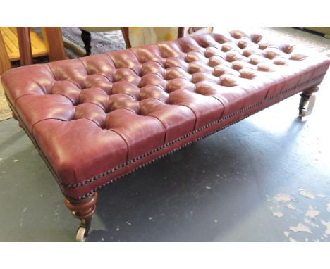 A Victorian rectangular footstool with deep buttoned burgundy leather upholstery over a stud frieze on turned mahogany legs w