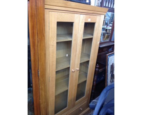 LIGHT OAK GLAZED BOOKCASE WITH LOWER DRAWER. W100CM