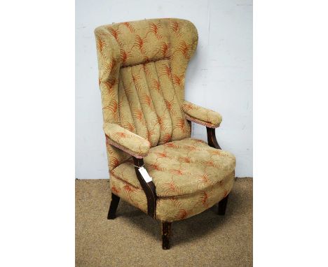 A 20th Century wingback armchair, the shaped and padded back, wings and arms above a padded seat, raised on tapering legs, 11