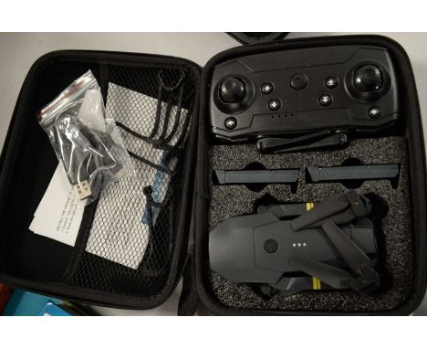 Collapsible drone, with camera lens, accompanied by remote control, USB cable and user manual, in carry case.