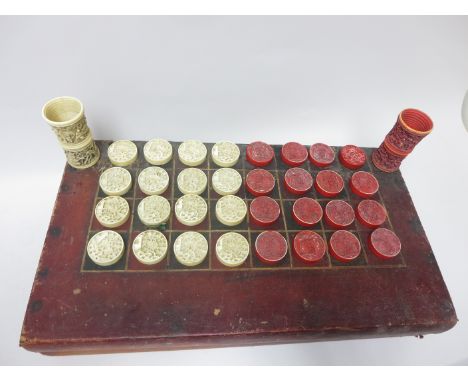 A 19th Century folding Games Box for Backgammon and Draughts containing sixteen and white and red stained ivory counters carv