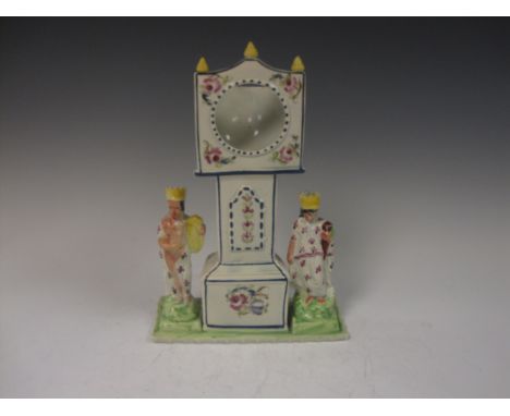 An early 19th Century Watch Holder with longcase clock style centre flanked by figures with crowns and colourful robes, on a 