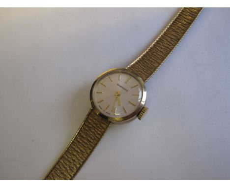 A Lady's Garrard Wristwatch the silvered dial with gold baton markers on integral bark effect 9ct gold bracelet