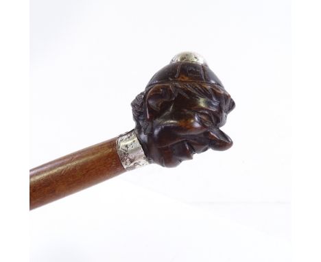 A walking stick with a carved wood handle in the form of a boy's head, unmarked silver mounts 