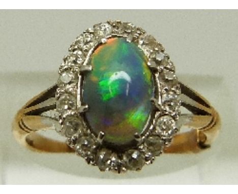 A Victorian 18ct gold ring set with a black opal cabochon surrounded by diamonds in a platinum setting, size K, 3.8g. 