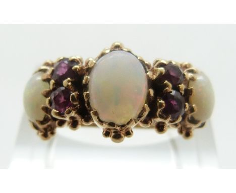 A Victorian ring set with three oval opal cabochons and four round cut rubies with foliate design to the shoulders, size N, 4