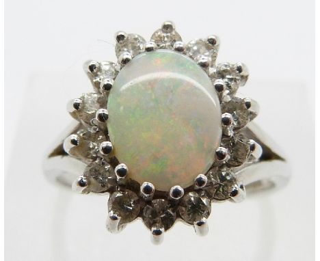 An 18ct white gold ring set with an oval opal cabochon surrounded by diamonds, size N, 3.6g