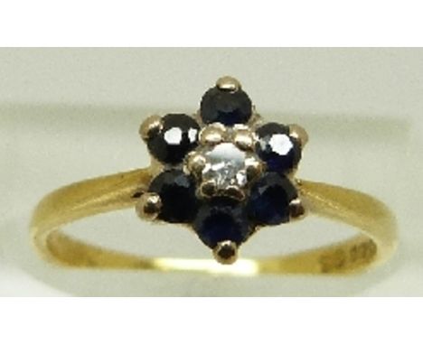 An 18ct gold ring set with a diamond surrounded by sapphires in a floral cluster, size K, 2.3g 