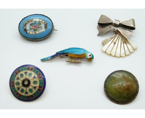 A white metal button set with enamel, an enamel parrot brooch, silver and pottery brooch, silver bow brooch with a mother of 