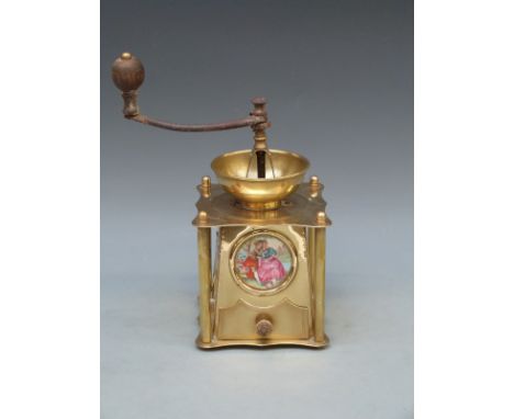 A brass coffee grinder with inset ceramic plaque, embossed decoration and turned wooden handle, 26cm tall