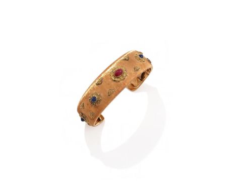 BUCCELLATI, A RUBY AND SAPPHIRE CUFF The torc bangle of textured finish, set with an oval cabochon ruby between cabochon sapp