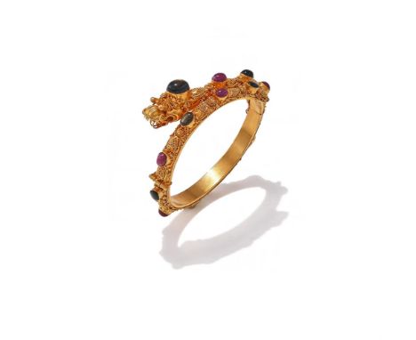 A RUBY AND BLACK STAR SAPPHIRE BANGLE The hinged bangle designed as a coiled serpent with beadwork decoration, collet set wit