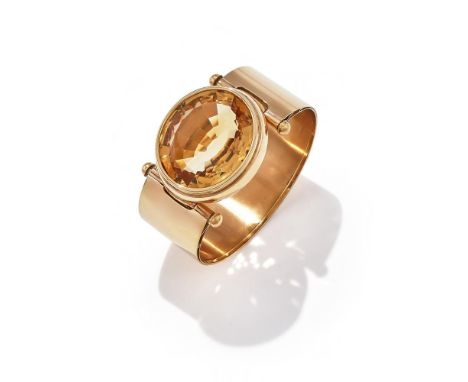MORONI, A CITRINE BANGLE The oval cut citrine within a polished collet setting, to a broad polished bangle, with a pin clasp,