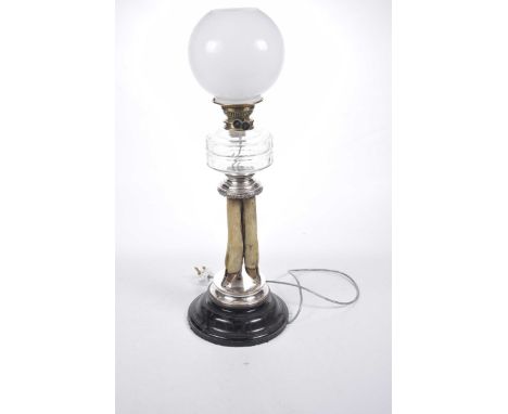 An unusual early 20th Century taxidermy oil lamp, (converted to electricity)The spreading circular ebonised base extending to