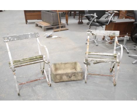 A pair of ironwork and slatted patio chairs, and a small stone troughThe two chairs with scrolling ironwork supports and rail