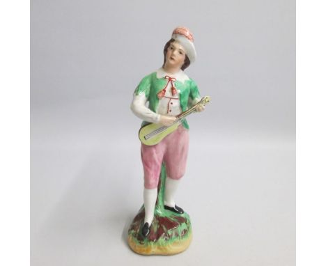 A late Kent Staffordshire figure of a male musician playing a mandolin, standing on a green and brown grassy mound base.
Date