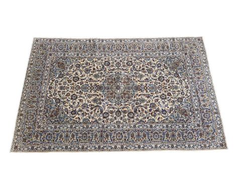 Kashan woollen carpet, the ivory field dispersed with palmettes centred with a floral medallion and bordered with a fawn and 
