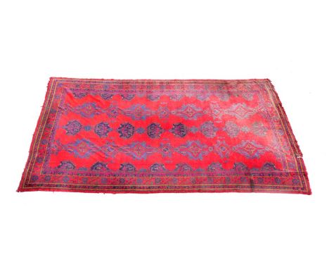 Large Turkey Ushak woollen carpet, the crimson field dispersed with blue medallions within a red and blue flowerhead border (