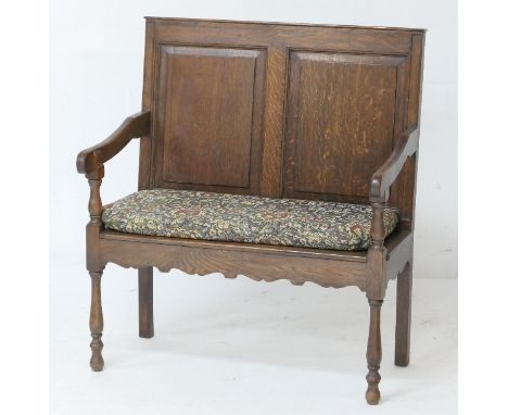 Small oak settle, late 19th Century, double fielded panel back, open arms, solid seat with a tapestry cushion, raised on turn