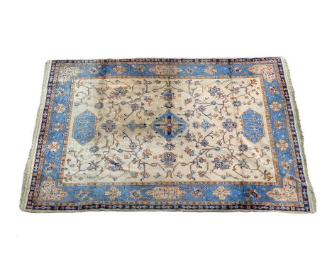 Heriz woollen carpet, beige ground with central blue medallions and flowering branches within a blue flowerhead border, size 