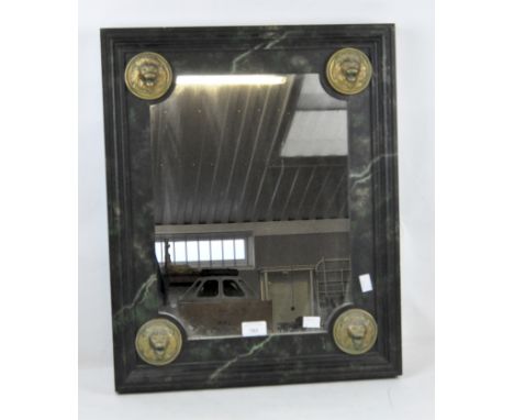 An ebonised wooden wall mirror of rectangular form painted to resemble marble, adorned with four lions head mounts, 57cm x 47