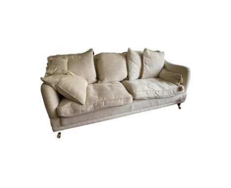 A large modern Knowle sofa in light beige/cream fabric. Raised on brass mounted castors. General wear commensurate with age a