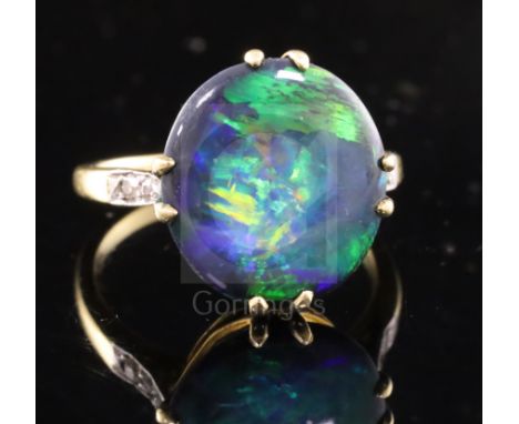 A 1920's 18ct gold, platinum and oval black opal dress ring with diamond set shoulders, size M.