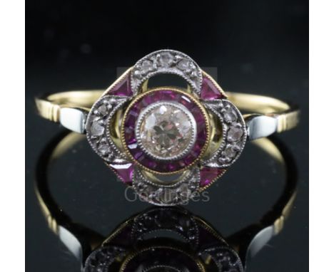 A 1920's gold and platinum, ruby and diamond set cluster ring, the pierced setting with central diamond, bordered with shaped