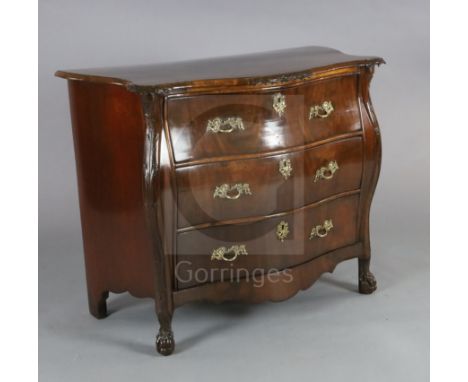 A late 19th century French flame mahogany bombe commode, with floral carved frieze and angles flanking three long drawers, on