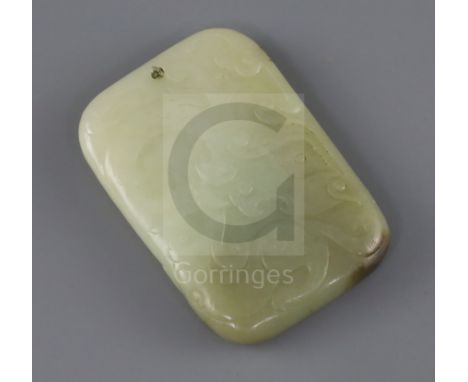 A Chinese pale celadon and brown jade plaque, 19th century, carved in relief with a dragon and taotie mask to one side and a 