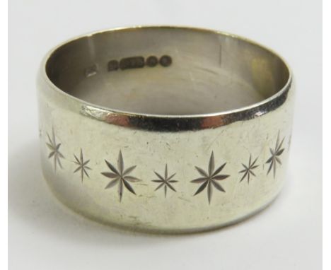 A wide 9ct white gold wedding band, decorated with engraved stars and a bevelled edge, approximately 10mm wide, finger size R