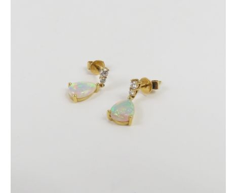 A pair of opal and diamond stud drop earrings, the pear shaped cabochon cut white opals in three claw settings and with two d