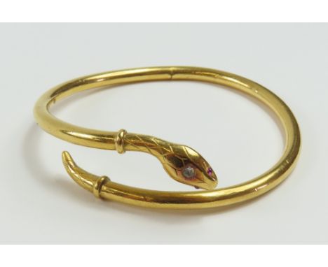 A 20th century snake bangle, with a lightly patterned head and tail, with ruby set eyes and a white stone to the top of the h