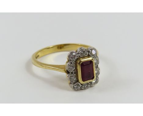 An 18ct gold ruby and diamond cluster ring, the rectangular shaped ruby with ten round diamonds surrounding it, the ruby appr