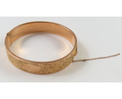 A rose gold half engraved, hollow, hinged bangle, 6cm internal diameter, acid tests as approximately 9ct gold, 13.9g gross